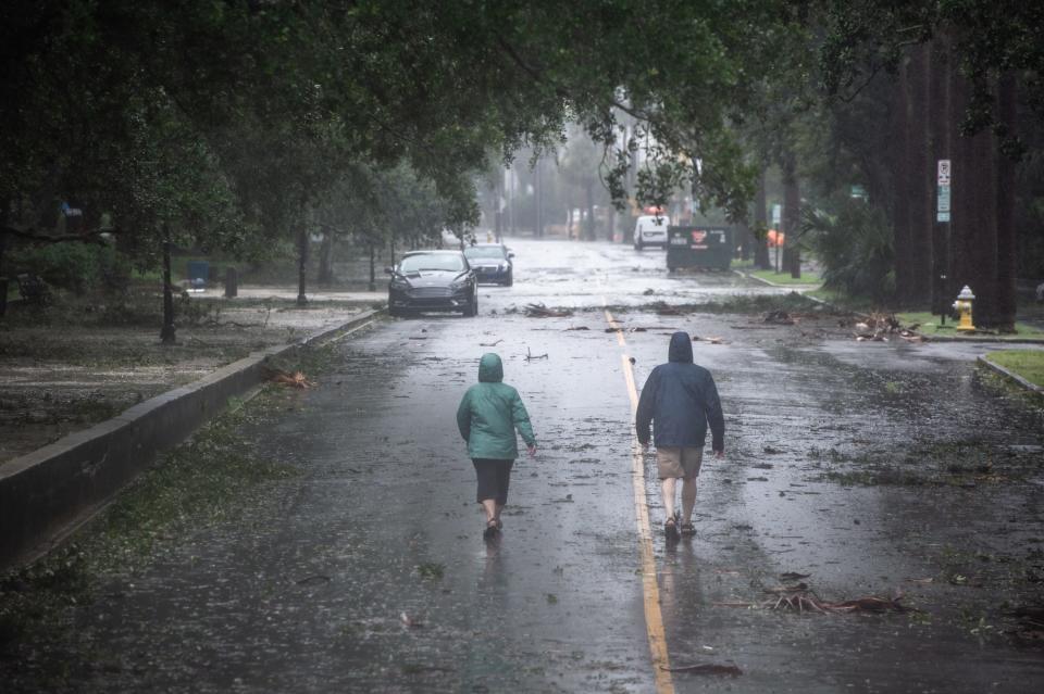 Two people walk down South Battery in Charleston, S.C., as Hurricane Dorian moves along the South Carolina coastline on Sept. 5, 2019.