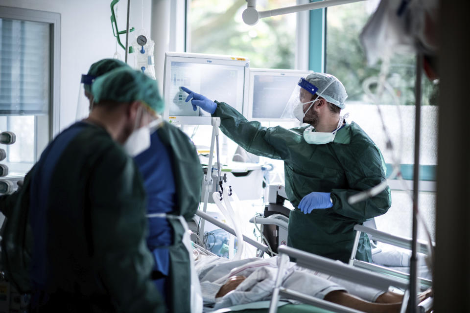 Nursing staff in protective equipment cares for a corona patient in a hospital in Essen, Germany, Wednesday, Oct. 28, 2020. People with a new coronavirus infection are treated in the intensive care unit IT2 in the Operative Centre II of the University Hospital Essen. (Fabian Strauch/dpa via AP)