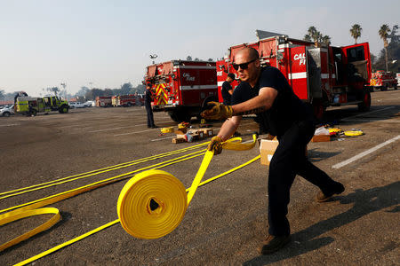 A Cal Fire firefighter unrolls new hoses before they are packed to fight wildfire at the Ventura County Fairgrounds fire camp during the Thomas fire in Ventura, California, U.S. December 12, 2017. REUTERS/Patrick T Fallon