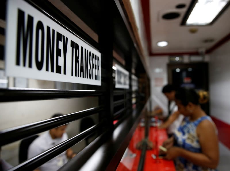 FILE PHOTO: Customers receive money from families working abroad at a money remittance center in Makati