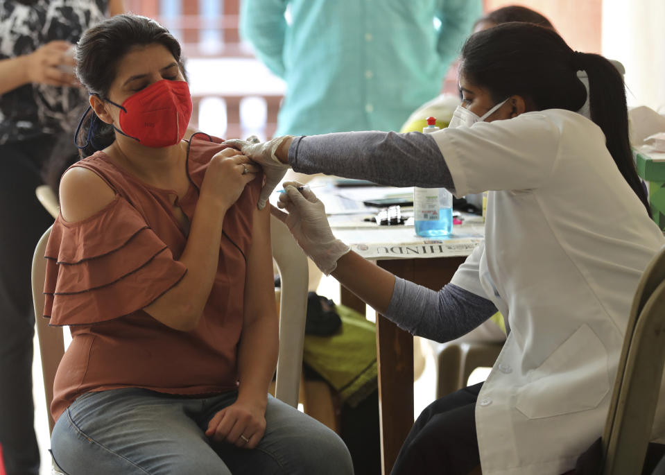 A woman reacts as she receives the AstraZeneca vaccine for COVID-19 at an apartment building in Bengaluru, India, Saturday, April 24, 2021. Indian authorities are scrambling to get medical oxygen to hospitals where COVID-19 patients are suffocating from low supplies. The effort Saturday comes as the country with the world's worst coronavirus surge set a new global daily record of infections for the third straight day. The 346,786 infections over the past day brought India's total past 16 million. (AP Photo/Aijaz Rahi)