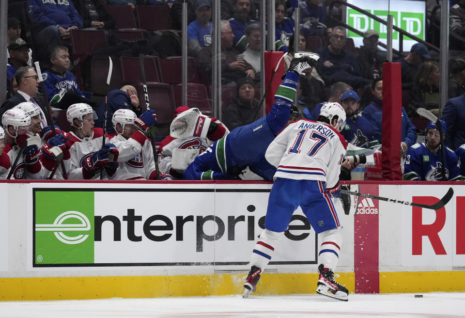 Montreal Canadiens' Josh Anderson (17) checks Vancouver Canucks' Riley Stillman into the Montreal bench during the second period of an NHL hockey game in Vancouver, British Columbia, Monday, Dec. 5, 2022. (Darryl Dyck/The Canadian Press via AP)