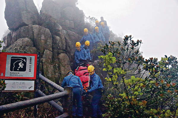 消防把死者遺體運上崖頂，旁邊可見「懸崖危險、切勿前進」的警告牌。