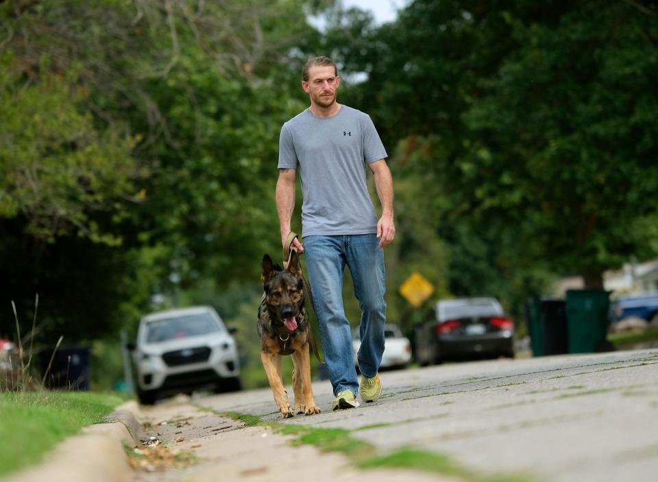 Casey McGarry, who has narcolepsy, walks with his service dog, Atlas.