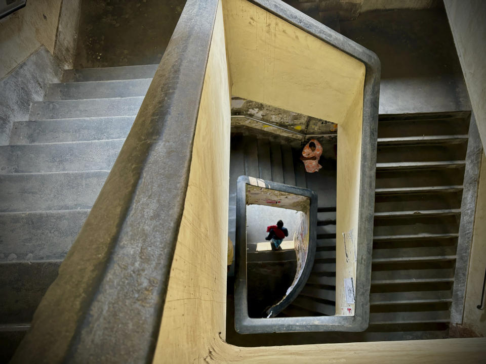 A homeless woman awaits alms sitting under the stairway of an old building in Kolkata, India, Sunday, Jan. 7, 2024. (AP Photo/Manish Swarup)