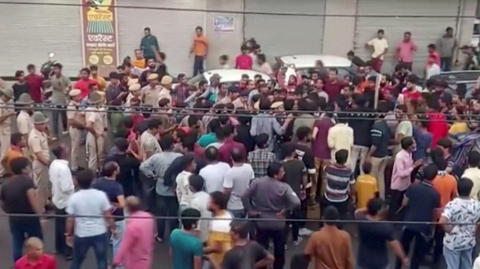 Police stand guard as people gather on road as tensions rise after the killing of a Hindu man in Udaipur, Rajasthan (ANI via Reuters)