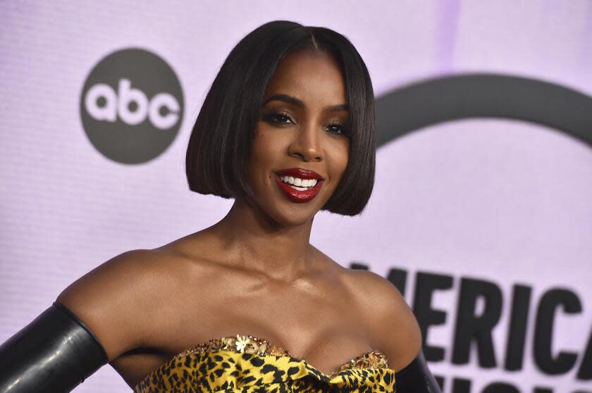 A woman with short black hair smiling and posing in a cheetah print dress and black gloves