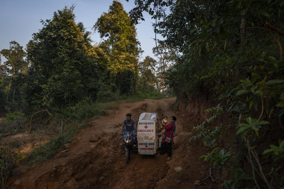 Lata Netam, right, a health worker, holds Dilesh son of Phagni Poyam, who is expecting a baby as they disembark from the ambulance before crossing a stream through Abhujmarh, or "the unknown hills," on their way to a health centre, near Kodoli, a remote village near Orchha in central India's Chhattisgarh state, Nov. 15, 2022. These ambulances, first deployed in 2014, reach inaccessible villages to bring pregnant women to an early referral center, a building close to the hospital where expectant mothers can stay under observation, routinely visit doctors if needed until they give birth. Since then the number of babies born in hospitals has doubled to a yearly average of about 162 births each year, from just 76 in 2014. The state has one of the highest rates of pregnancy-related deaths for mothers in India, about 1.5 times the national average, with 137 pregnancy related deaths for mothers per 100,000 births. (AP Photo/Altaf Qadri)