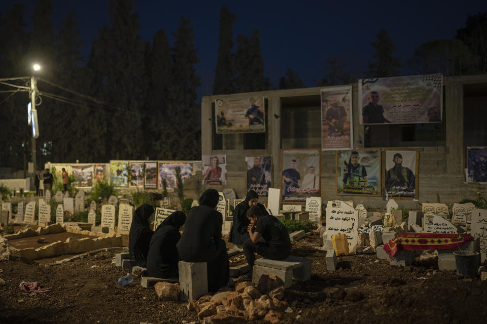 Family members sit next to the grave of Odei, 22, in Jenin, West Bank, Saturday, June 8, 2024. Odei was killed by Israeli forces during a raid inside the Jenin refugee camp. (AP Photo/Bram Janssen)