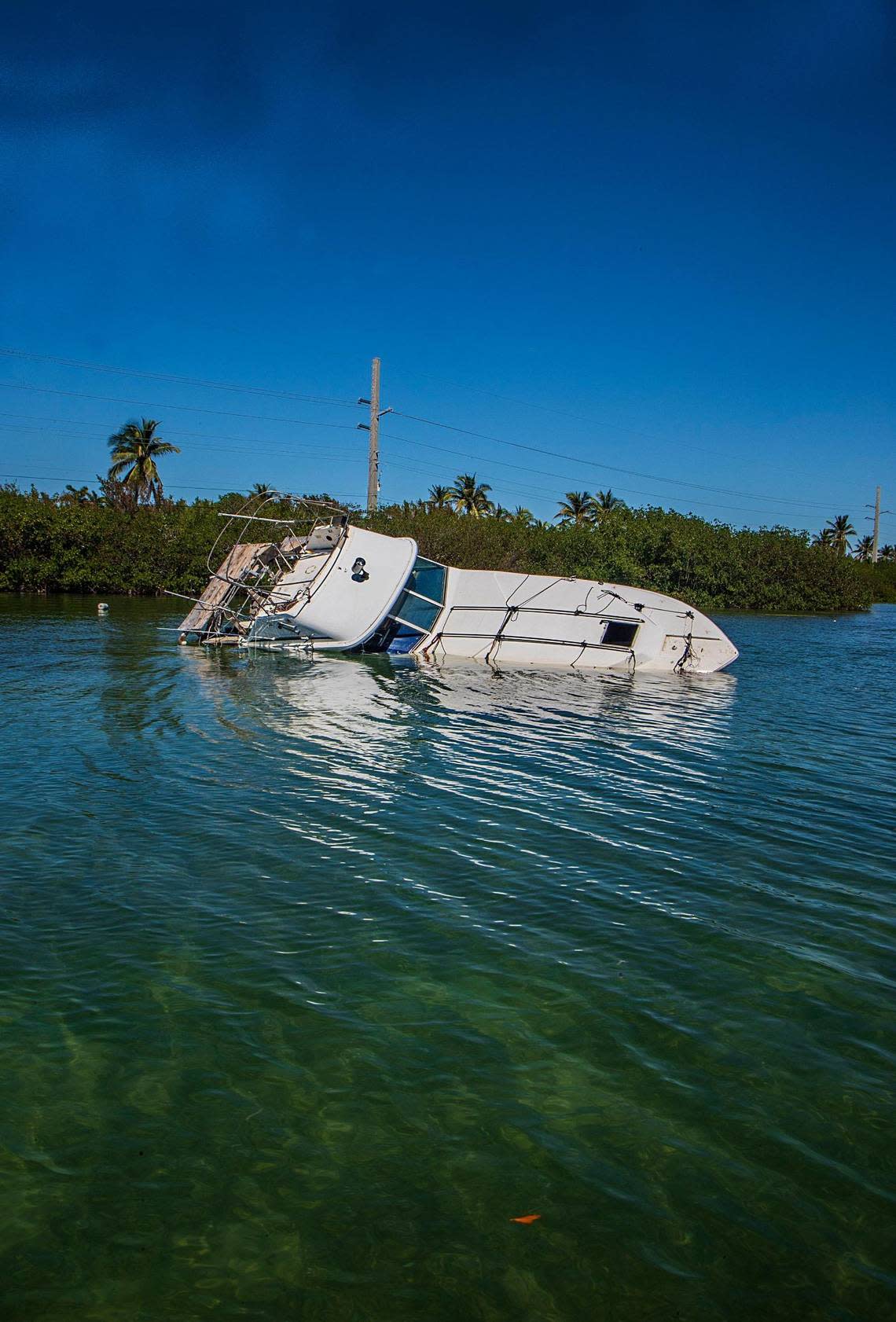 A boat lists on its side in shallow water off Sugarloaf Key Thursday, Oct. 27, 2022. The boat is one of more than 100 displaced vessels resulting from Hurricane Ian, which passed by the Florida Keys on Sept. 27, 2022.