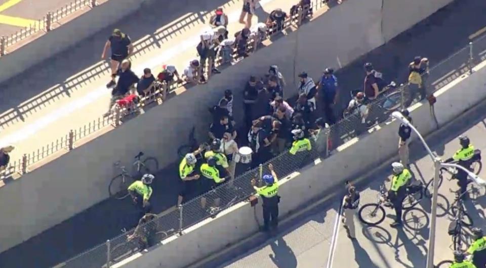Police officers with protesters on the Brooklyn Bridge. CBS
