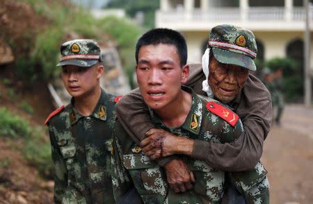 A paramilitary policeman carries an elderly man on his back after an earthquake hit Ludian county of Zhaotong, Yunnan province August 3, 2014. REUTERS/China Daily