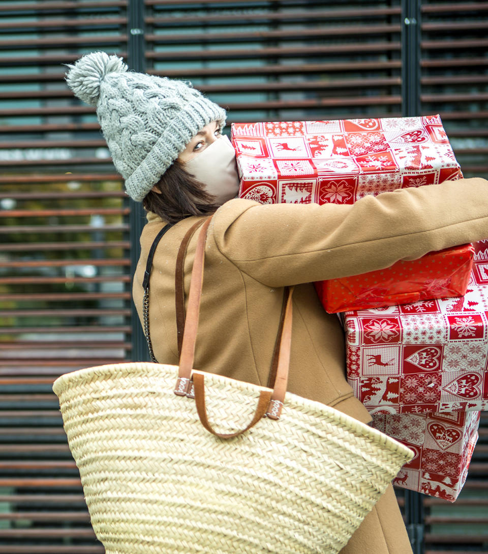 Woman holding Christmas gift boxes wearing a mask