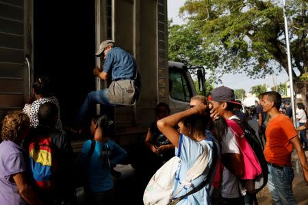 A man tries to get on a cargo truck used as public transportation in Valencia, Venezuela July 11, 2018. REUTERS/Marco Bello