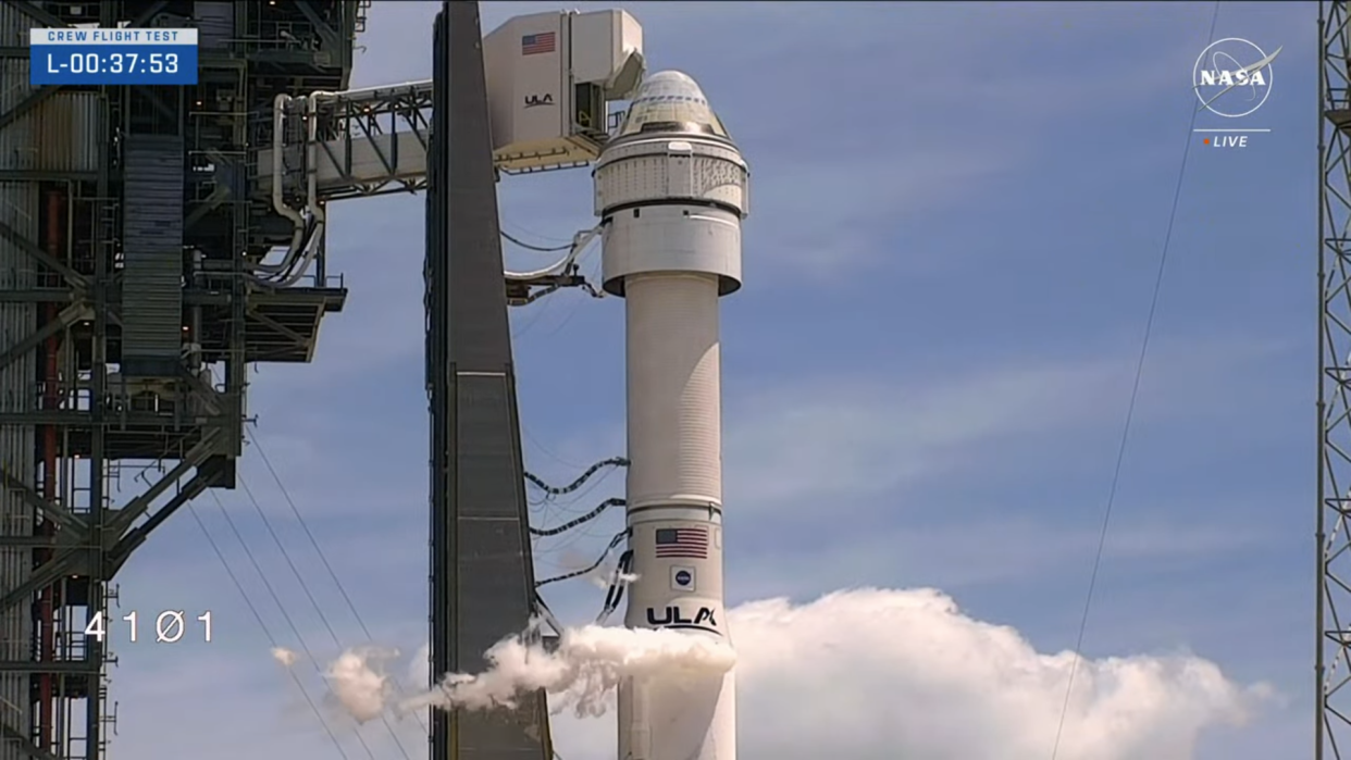  An Atlas V rocket and white Starliner capsule on the launch pad as its crew access arm moves clear. 