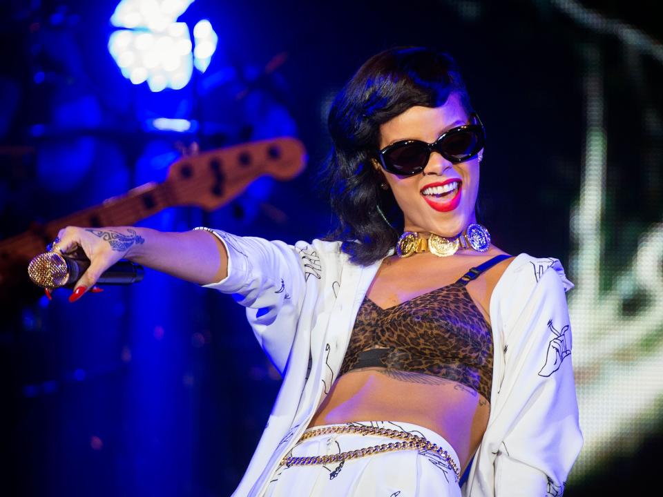 Rihanna on tour in 2012 wearing sunglasses holding a microphone