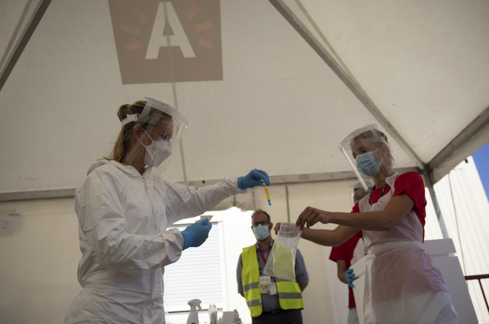 FILE - In this Wednesday, Aug. 5, 2020 file photo, Healthcare workers put a nasal swab sample from a patient into a plastic bag during a test day at a drive-thru COVID-19 testing site in Antwerp, Belgium. Small, yet so divided, Belgium is hit hard again by the pandemic, and now has some of the worst results to show in Europe during the resurgence of the Coronavirus, it is revealed Tuesday Oct. 27, 2020. (AP Photo/Virginia Mayo, File)