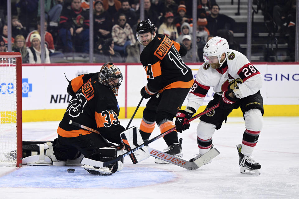 Ottawa Senators' Claude Giroux, right, scores a goal past Philadelphia Flyers goaltender Samuel Ersson (33) and the defense of Sean Couturier (14) during the third period of an NHL hockey game, Sunday, Jan. 21, 2024, in Philadelphia. (AP Photo/Derik Hamilton)