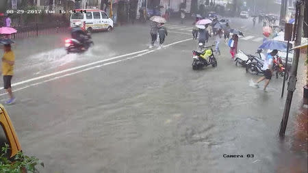 People walk under umbrellas during heavy rains in Parel neighbourhood of Mumbai, India, August 29, 2017 in this still image obtained from a CCTV camera. TWITTER/@VIVEK_J_SINGH via REUTERS