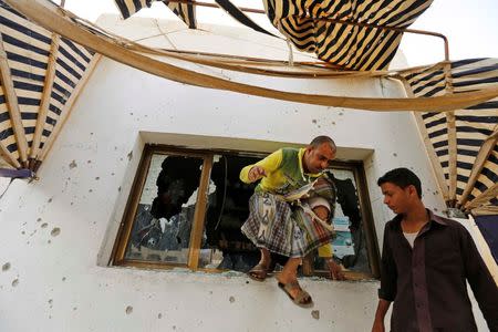 A worker jumps out of a damaged window of a school cafe at an area where fighting is going on between government forces and Shi'ite Houthi rebels in Sanaa September 19, 2014. REUTERS/Khaled Abdullah