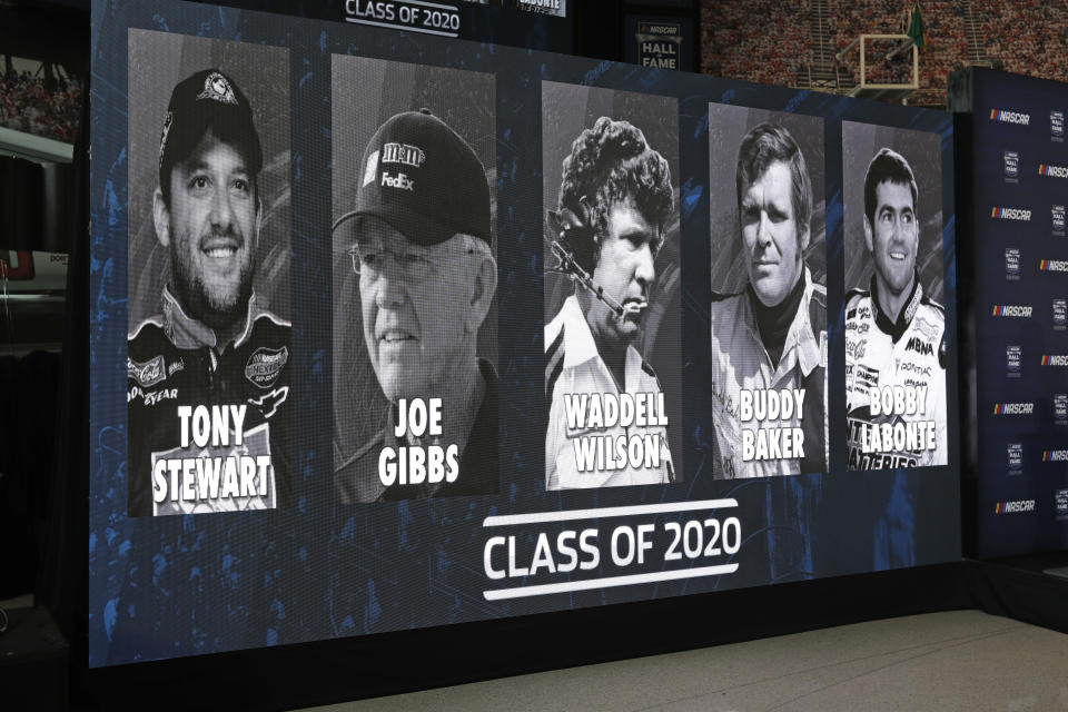 FILE - In this May 22, 2019, file photo, images of NASCAR's Hall of Fame Class of 2020, from left, Tony Stewart, Joe Gibbs, Waddell Wilson, Buddy Baker and Bobby Labonte are shown on a screen after an announcement in Charlotte, N.C. (AP Photo/Chuck Burton, File)