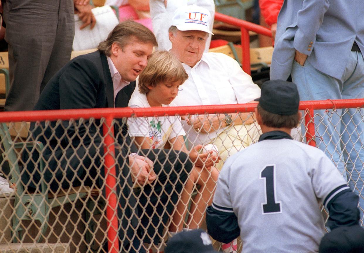 New York Yankees manager Billy Martin, right, meets developer Donald Trump at Municipal Stadium in West Palm Beach on March 26, 1988.  Seated with Trump are his son Donald, Jr., 10, with a ball given him by Martin and Yankees owner George Steinbrenner during the game with the Montreal Expos.