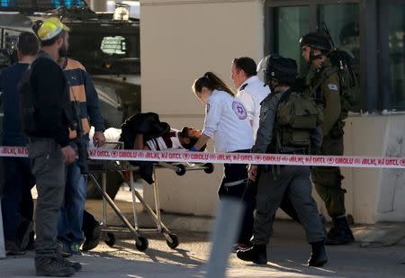 Israeli medics evacuate a Palestinian man, who a police spokeswoman said was shot and wounded by Israeli police during a car-ramming attempt at the West Bank checkpoint of Qalandia, near Ramallah, December 18, 2015. REUTERS/Mohamad Torokman