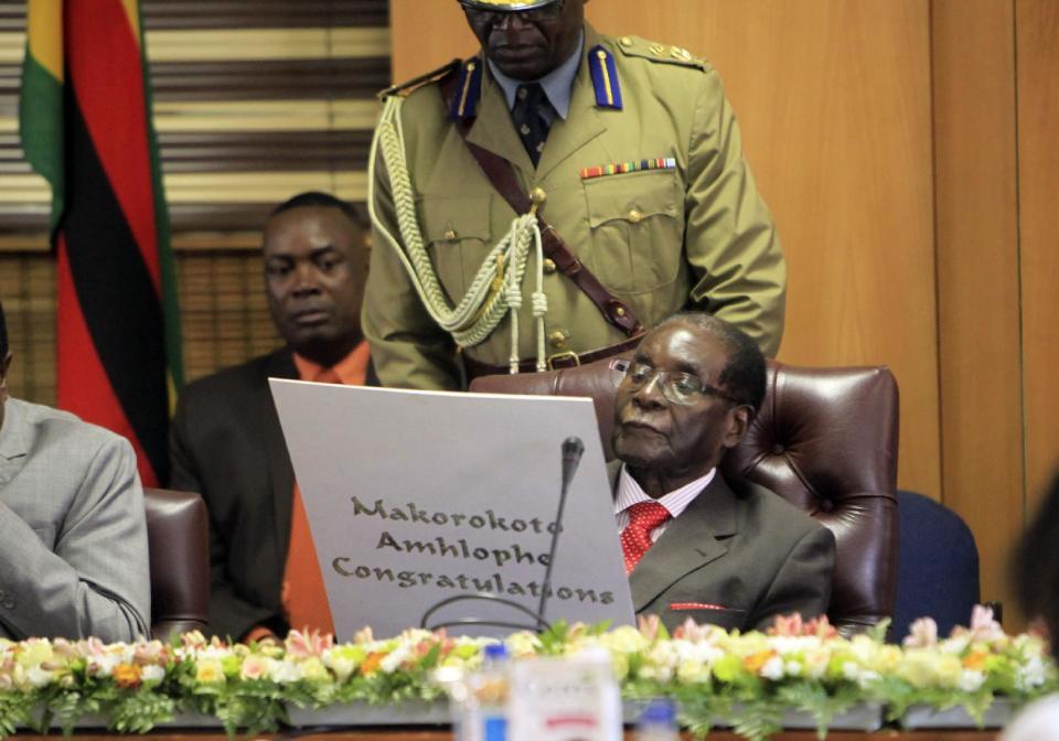 Zimbabwe's President Robert Mugabe reads his birthday card as he marks his 93rd birthday at his offices in Harare, Tuesday, Feb. 21, 2017. Mugabe described his wife Grace, an increasingly political figure, as "fireworks" in an interview marking his 93rd birthday. (AP Photo/Tsvangirayi Mukwazhi)