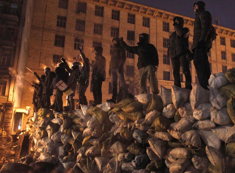 Anti-government protesters stand on a barricade during a rally in Kiev