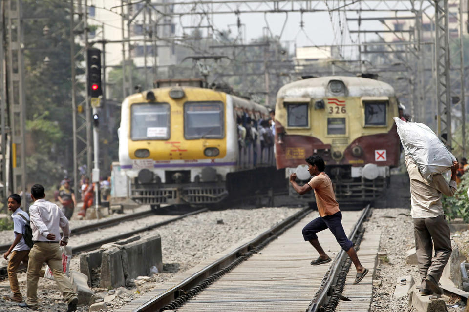 An Indian boy runs across a rail track in front of a running train in Mumbai, India.