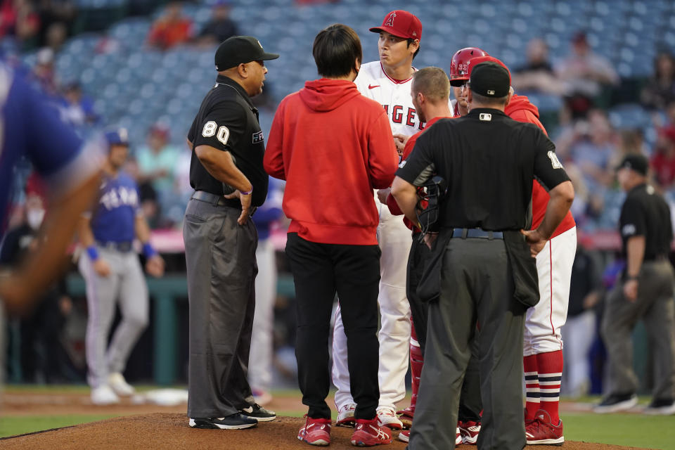 Los Angeles Angels starting pitcher Shohei Ohtani (17) is checked out on the mound after being hit by a sharp ground ball hit by Texas Rangers' Nathaniel Lowe during the first inning of a baseball game Friday, Sep. 3, 2021, in Anaheim, Calif. (AP Photo/Ashley Landis)