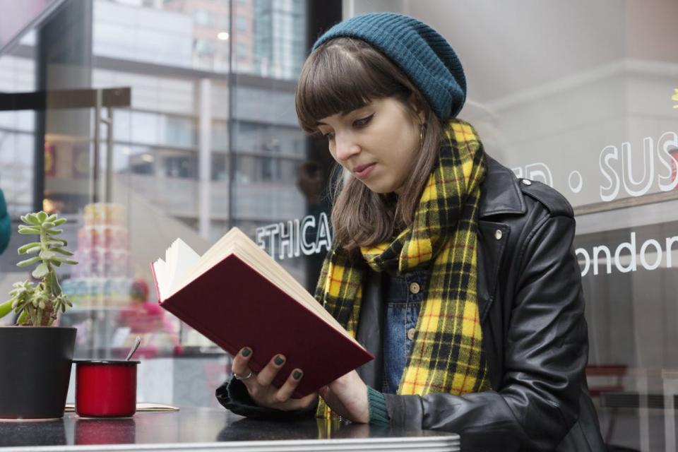 Sitting outside a cafe, a woman reads a book