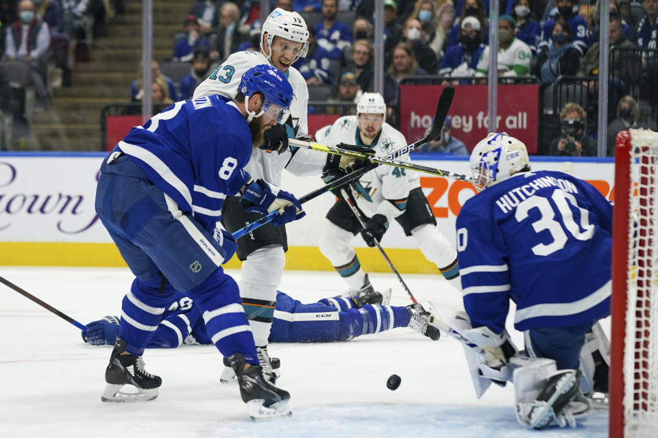 San Jose Sharks forward Nick Bonino (13) is defended by Toronto Maple Leafs defenseman Jake Muzzin (8) after Maple Leafs goaltender Michael Hutchinson (30) gave up a rebound during the first period of an NHL hockey game Friday, Oct. 22, 2021, in Toronto. (Evan Buhler/The Canadian Press via AP)