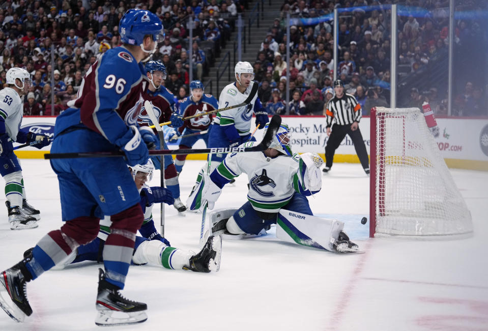 Vancouver Canucks goaltender Spencer Martin (30) lets a goal slip past off the stick of Colorado Avalanche right wing Mikko Rantanen (96) during the first period of an NHL hockey game Wednesday, Nov. 23, 2022, in Denver. (AP Photo/Jack Dempsey)