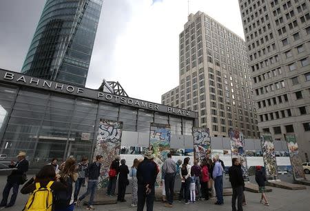 Tourists look at the remaining parts of the Berlin Wall placed in front of the Ritz Carlton Hotel (C), in Berlin June 14, 2013. REUTERS/Fabrizio Bensch