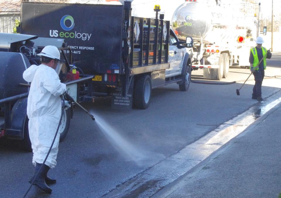 Employees of US Ecology on Sunday clean up a mixture of fuel and oil along Locust Street, near East Street in downtown Redding. About 4,000 gallons of the toxic mixture spilled into the streets and waterways after a tanker truck tipped over in the area on Friday.