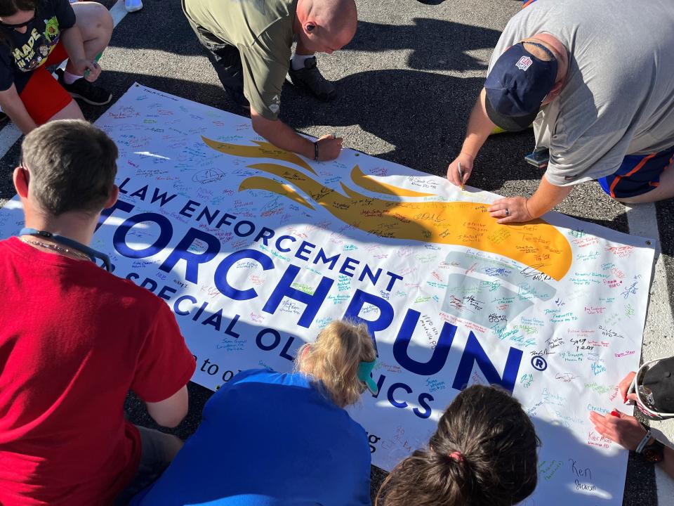 Law Enforcement Torch Run participants autograph this sign to commemorate the local edition of the 2022 event held on Friday, June 24, 2022, in Marion.