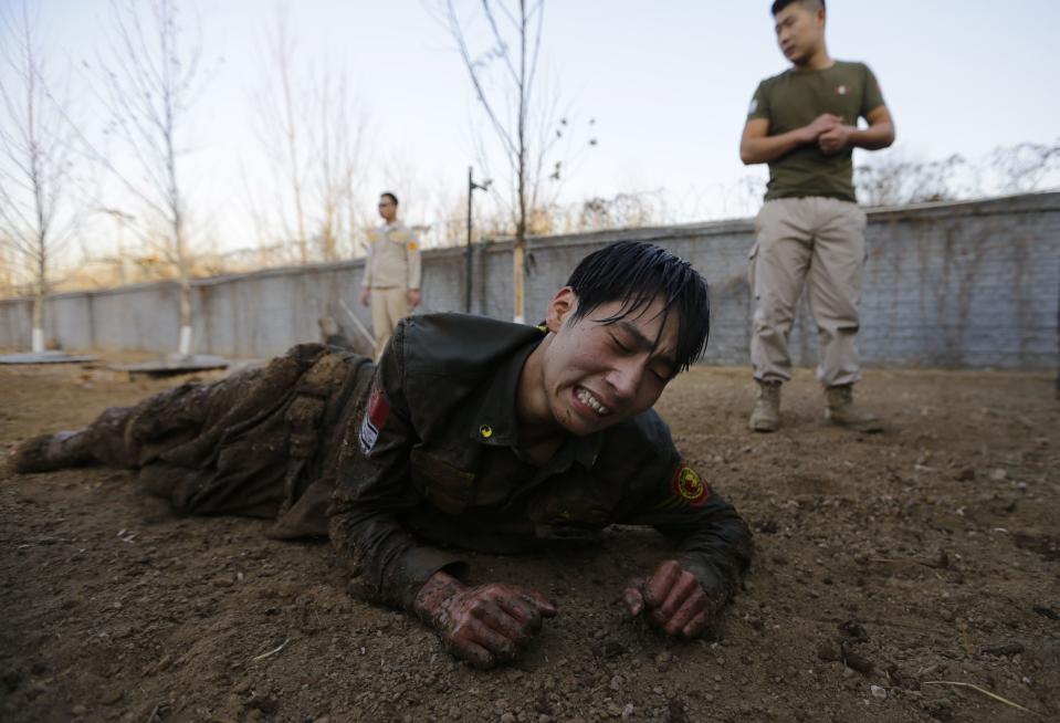 Student reacts as he crawls on the ground during Tianjiao Special Guard/Security Consultant training on the outskirts of Beijing