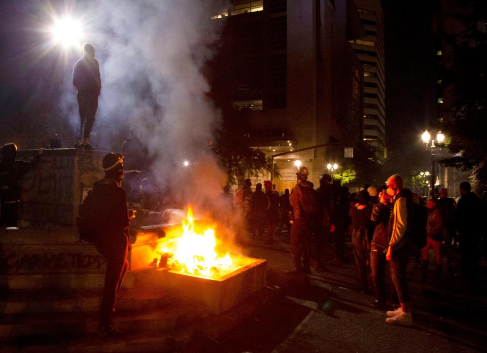 FILE - In this July 4, 2020, file photo, protesters gather near a fire in downtown Portland, Ore. Oregon's largest city is in crisis as violent protests have wracked downtown for weeks.