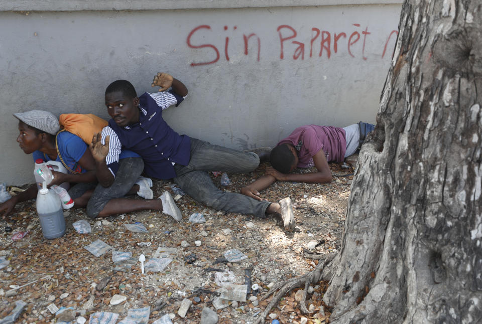 Demonstrators who were carrying the coffins with the remains of two victims of the ongoing violence take shelter after clashes erupted between demonstrators and the Presidential Guard, near the Presidential Palace in Port-au-Prince, Haiti, Wednesday, Oct. 16, 2019. At last two people were injured in the clashes the while thousands across Haiti attended funerals for protesters who have died in ongoing demonstrations aimed at ousting President Jovenel Moise. (AP Photo/Rebecca Blackwell)