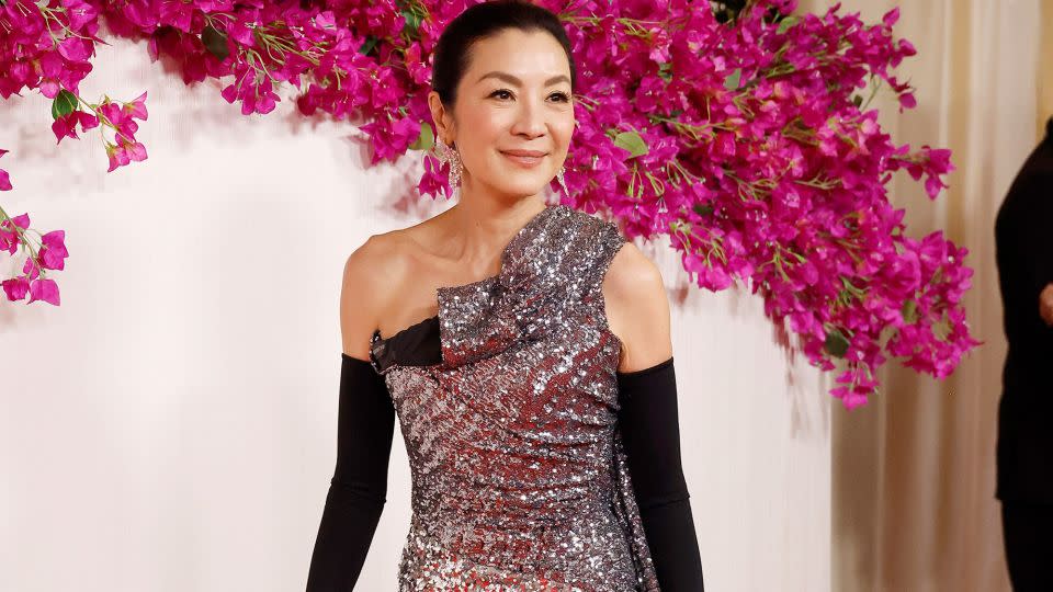 Michelle Yeoh stunned in a custom Balenciaga gown, sleek black opera gloves and Cindy Chao earrings made from diamonds and sapphires. - Mike Coppola/Getty Images