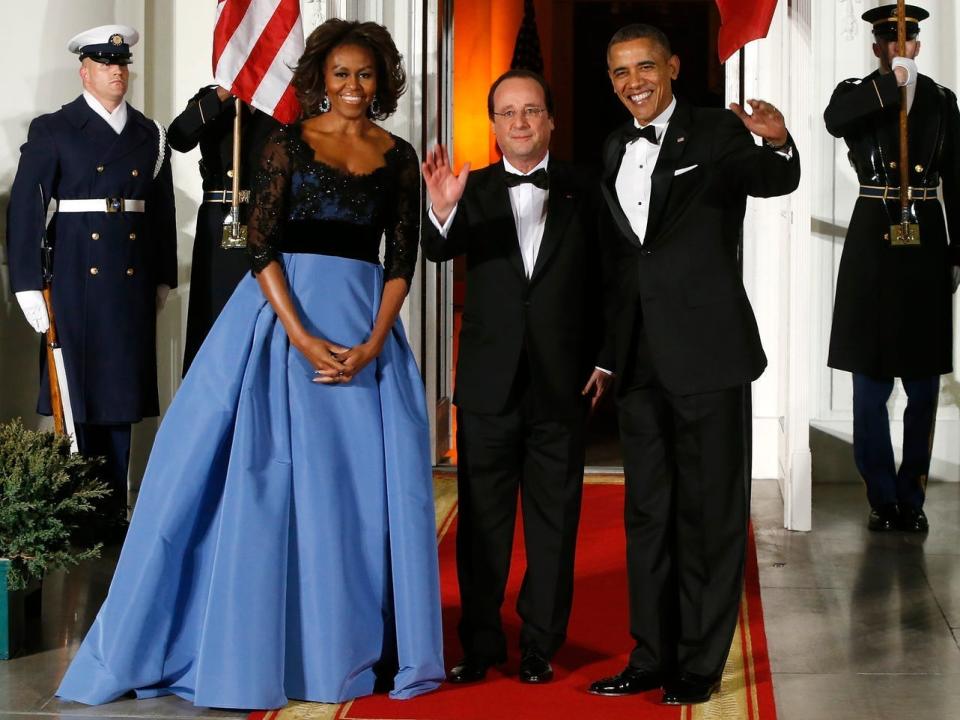 The Obamas at a state dinner for France. Michelle Obama wears a dress with a black bodice and blue skirt.