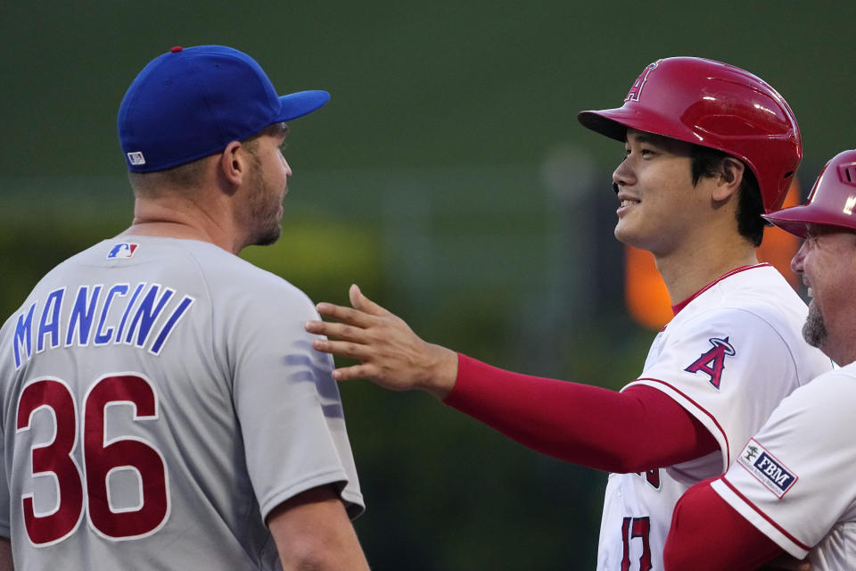 Los Angeles Angels' Shohei Ohtani, center, talks with Chicago Cubs first baseman Trey Mancini after he hit a swingle during the second inning of a baseball game Thursday, June 8, 2023, in Anaheim, Calif. (AP Photo/Mark J. Terrill)