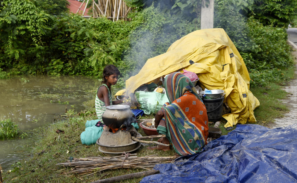 A family takes shelter on a high-land in a flood-affected in Panikhaiti in Kamrup District, Assam, India on Tuesday, on July 14, 2020. Villages in Assam were flooded due to heavy rains. The rising water level inundated houses, residents were forced to move to a safer place. (Photo by Hafiz Ahmed/Anadolu Agency via Getty Images)