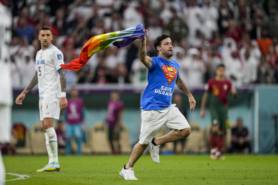 A pitch invader runs across the field with a rainbow flag during the World Cup group H soccer match between Portugal and Uruguay, at the Lusail Stadium in Lusail, Qatar, Monday, Nov. 28, 2022. (AP Photo/Abbie Parr)