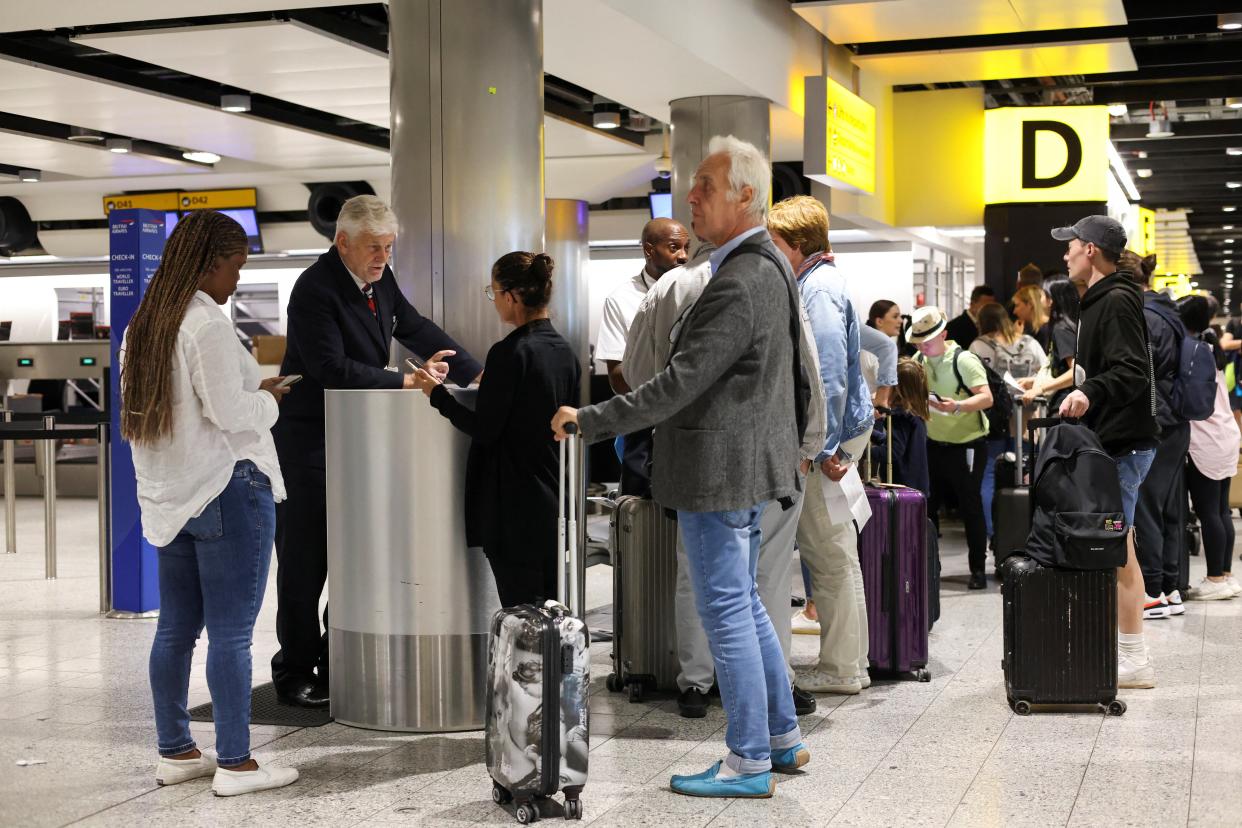 A British Airways staff member speaks to a passenger at Heathrow Airport Terminal 3 (REUTERS)