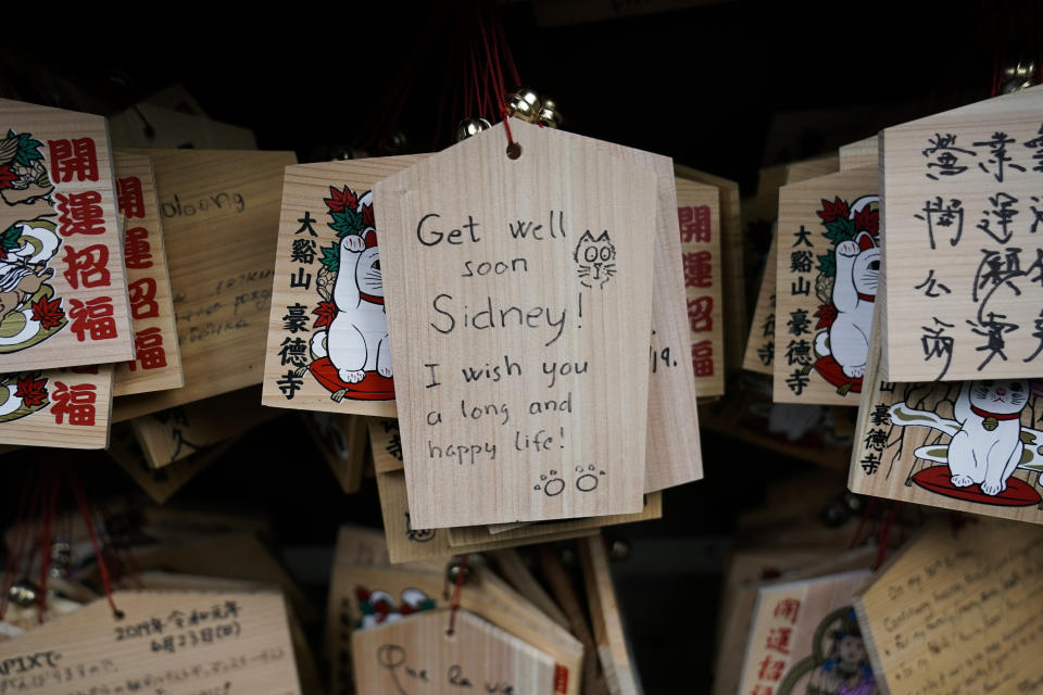 In this July 2, 2019, photo, a prayer is written on a wooden panel donned with an image of a beckoning cat at Gotokuji Temple in Tokyo. According to a centuries-old legend provided by the temple, Gotokuji, a Buddhist temple located in the quiet neighborhood of Setagaya, is the birthplace of beckoning cats, the famous cat figurines that are widely believed to bring good luck and prosperity to home and businesses. Some visitors come just to snap a few photos, while others make a trip to the temple to pray and make wishes. (AP Photo/Jae C. Hong)