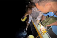 In this photo provided by the Philippine Coast Guard, Philippine Coast Guard personnel plucks a survivor from the waters near a burning MV Lady Mary Joy at Basilan, southern Philippines early Thursday March 30, 2023. More than a dozen people died while other were reported missing after an inter-island cargo and passenger ferry with about 200 passengers and crew onboard caught fire close to midnight in the southern Philippines, a provincial governor said Thursday. (Philippine Coast Guard via AP)