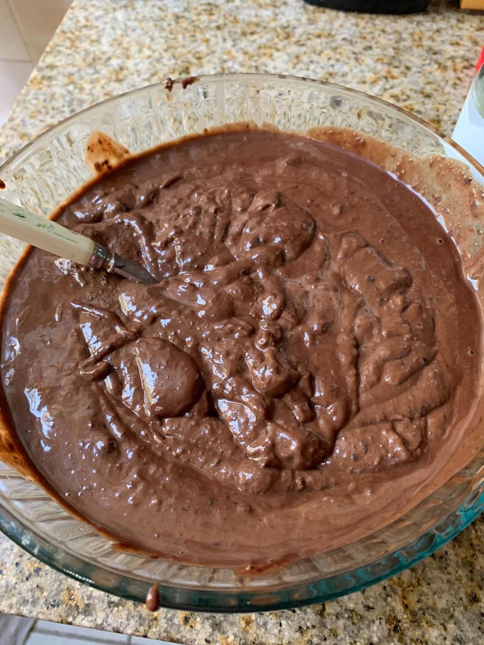 a glass pyrex bowl full of chocolate brownie batter