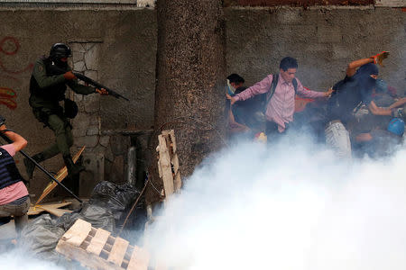 Demonstrators run away from a riot security force member at a rally against Venezuelan President Nicolas Maduro's government in Caracas, Venezuela. REUTERS/Carlos Garcia Rawlins